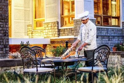 Chef placing dishes on the dining table set outdoors at The Indus Valley Leh, luxury hotel in Leh Ladakh