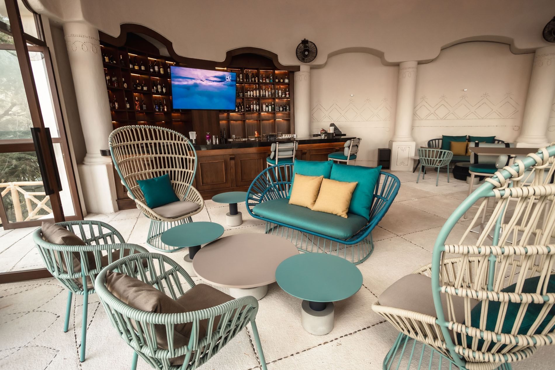 Modern lounge in Maricia Bar featuring stylish wicker chairs and vibrant turquoise cushions at Quinta Real Acapulco