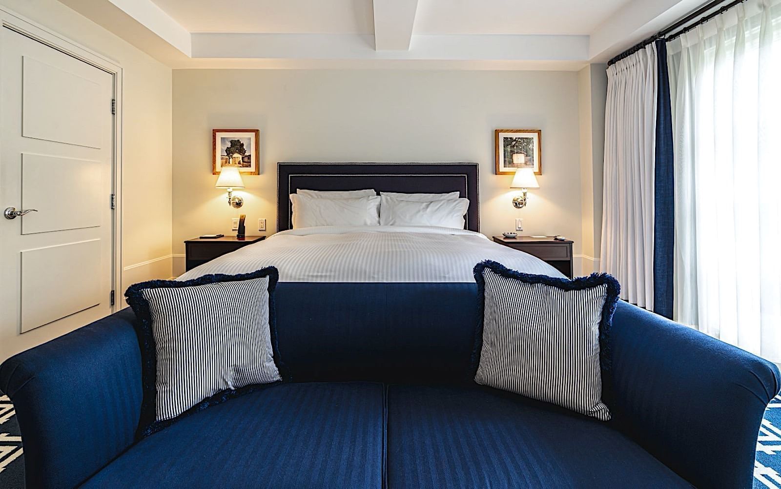 Well-appointed room with a comfy bed, blue couch, and hanging artwork at El Prado Hotel