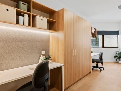 Modern office space with wooden desk, shelves, and chair at UniLodge Brisbane City.