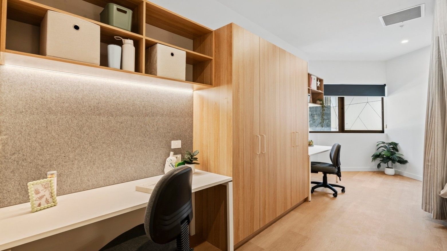 Modern office space with wooden desk, shelves, and chair at UniLodge Brisbane City.