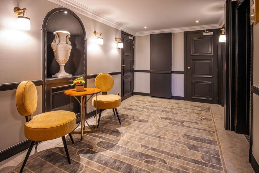 Seating area featuring yellow velvet chairs beside a classical vase in a chic, lit alcove at Hotel Barsey by Warwick