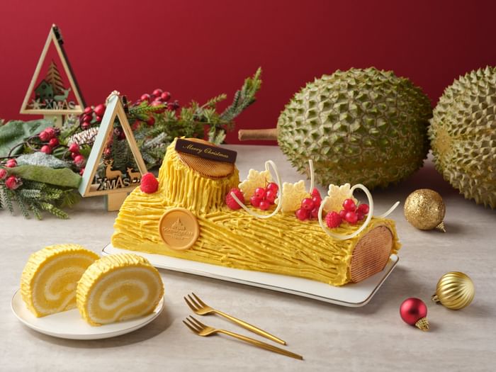A luxurious durian Yule Log cake with a Goodwood Park Hotel medallion surrounded by durians for Christmas