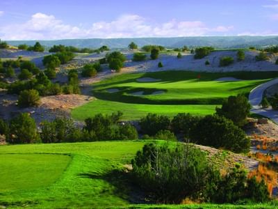 Scenic Towa Golf Club course near Hilton Santa Fe Buffalo Thunder, featuring sand traps and a partly cloudy day