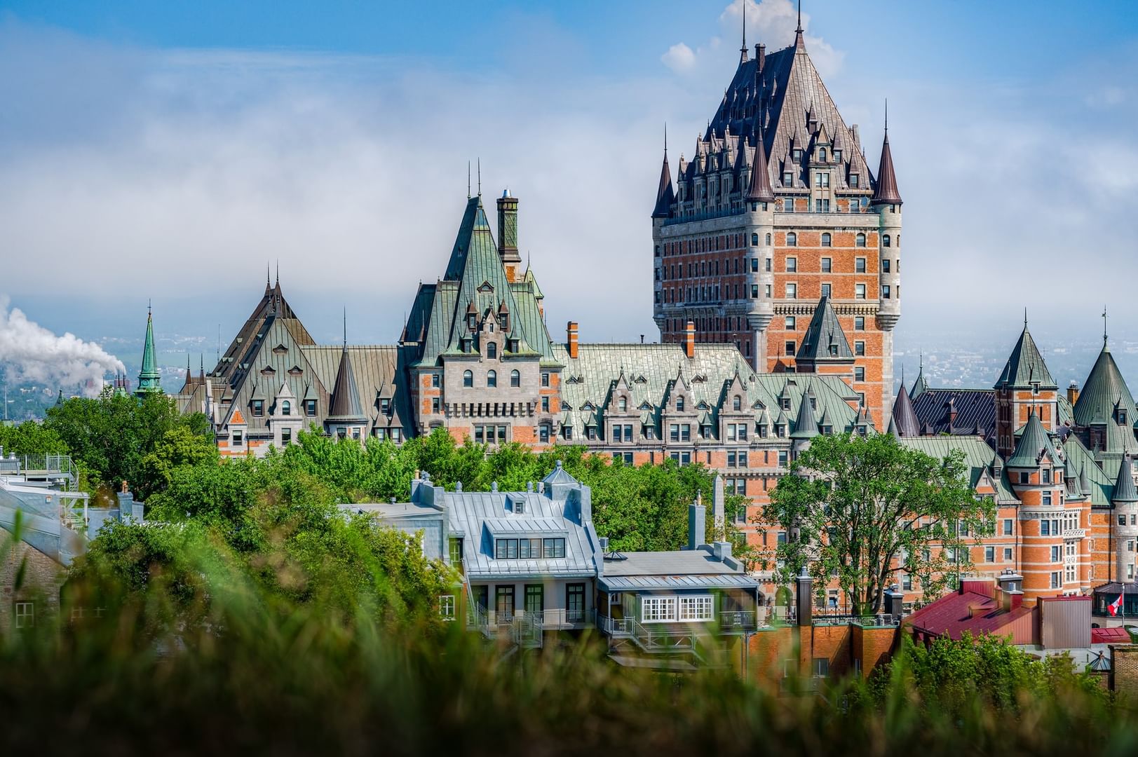 Château historique avec architecture gothique et arbres verdoyants sous un ciel bleu clair chez Warwick Le Crystal Montreal