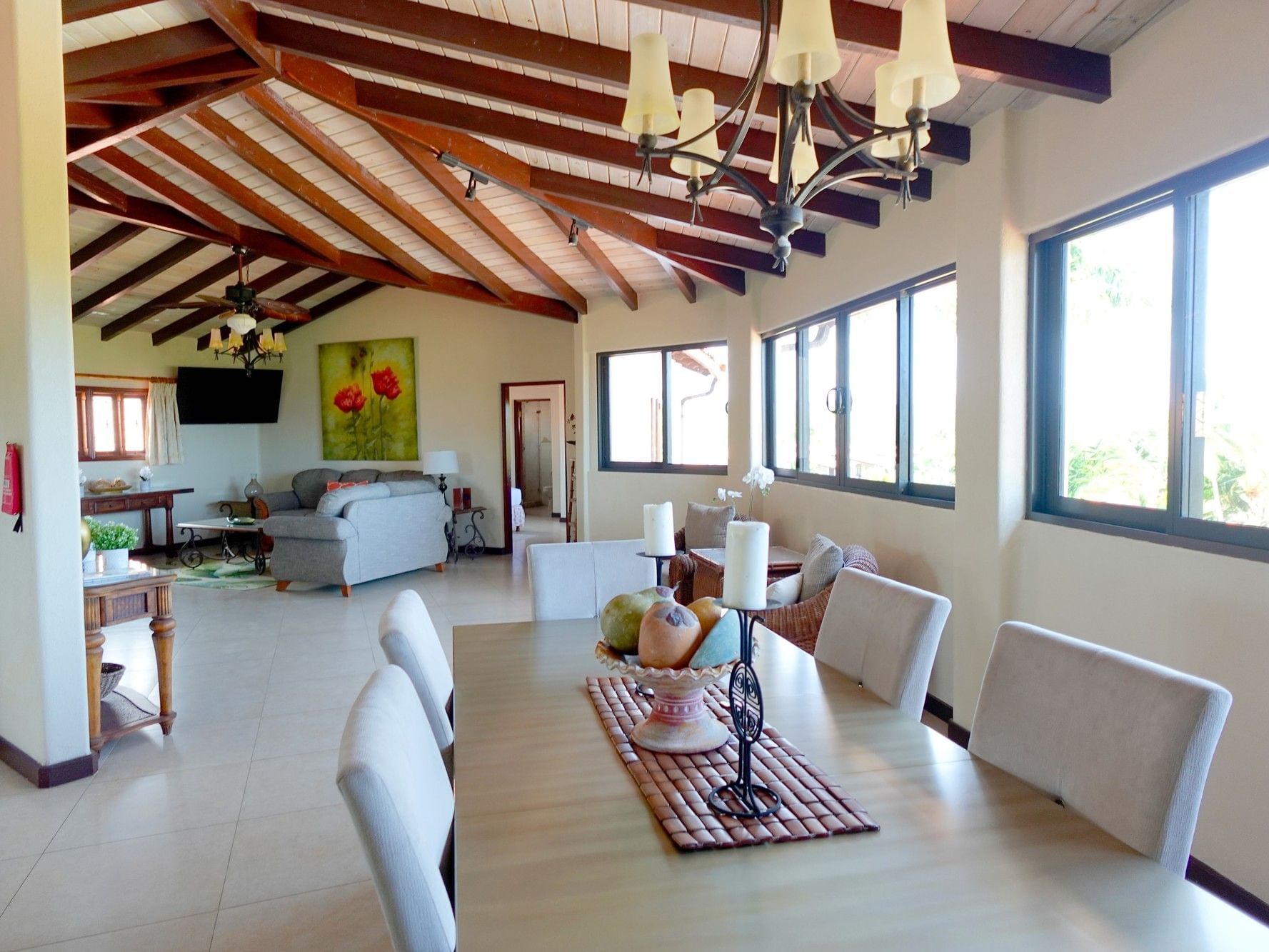 Long wooden dining table under a chandelier with open balcony view in the penthouse at Sugar Cane Club Hotel & Spa
