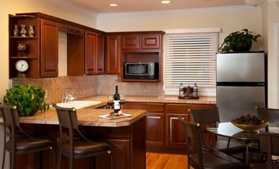 Kitchen with dark wood cabinets, a dining table with chairs, with bar stools in Presidential Cottage at The Stanley Hotel