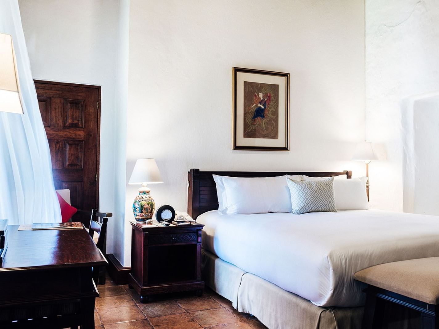 Work desk, ottoman, and nightstand by the cozy bed in the King Grand Class Suite at Quinta Real Oaxaca