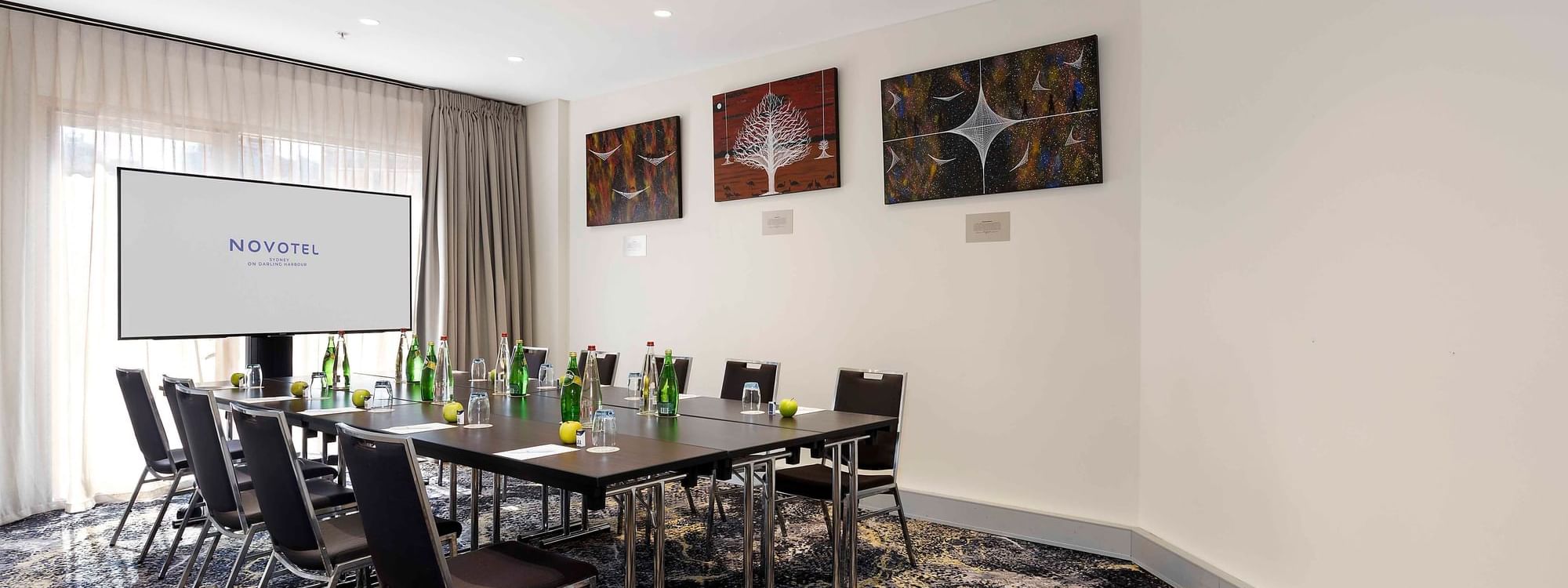 Boardroom set-up facing the projector screen in The Mudgee Boardroom at Novotel Sydney on Darling Harbour