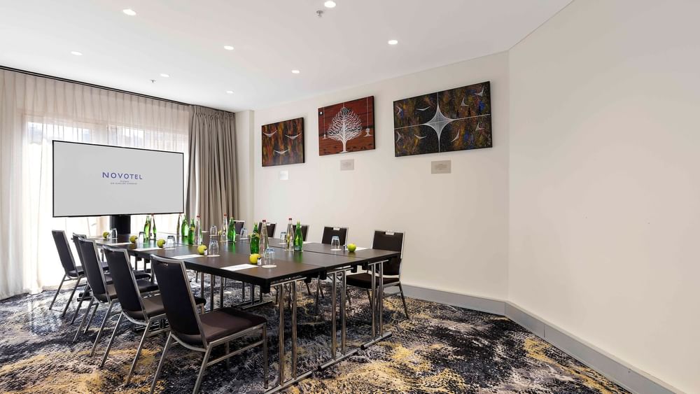 Boardroom set-up facing the projector screen in The Mudgee Boardroom at Novotel Sydney on Darling Harbour