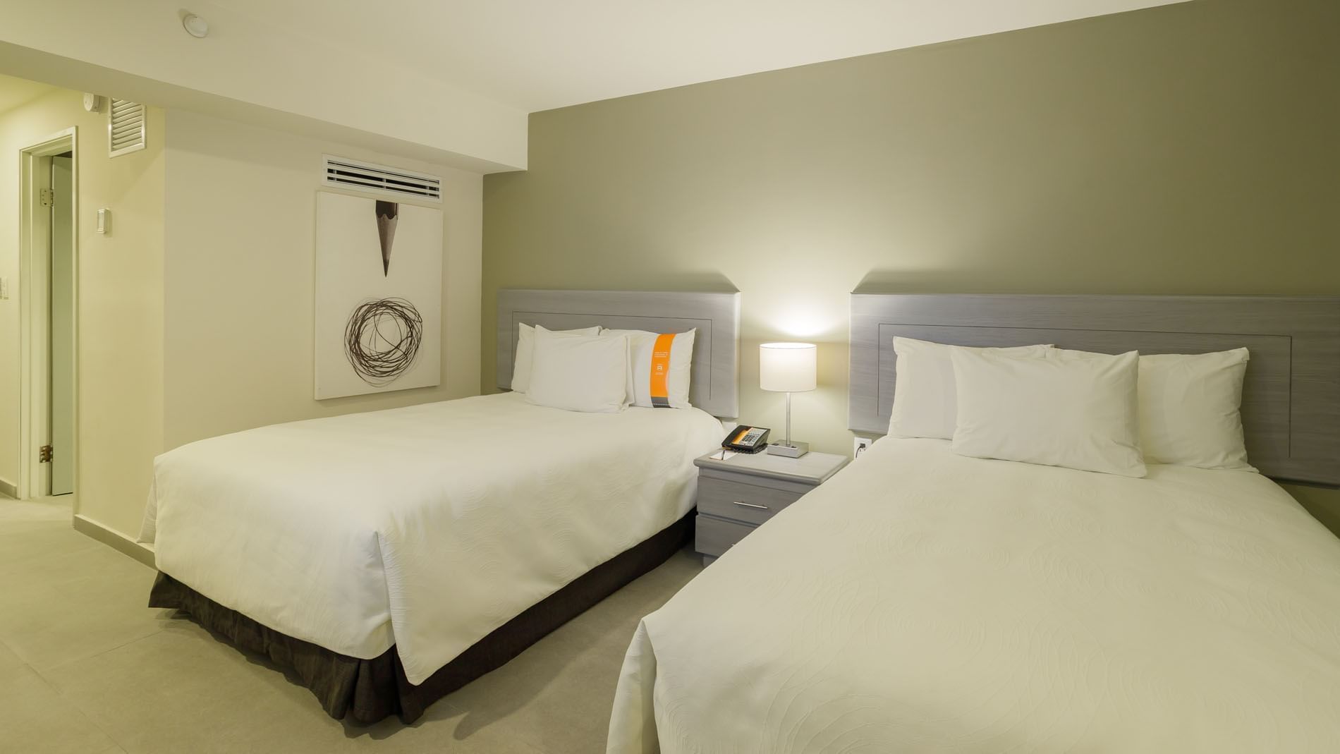 2 Double Deluxe room with white bedding, a lit bedside lamp, and simple wall art at Real Inn Mexicali