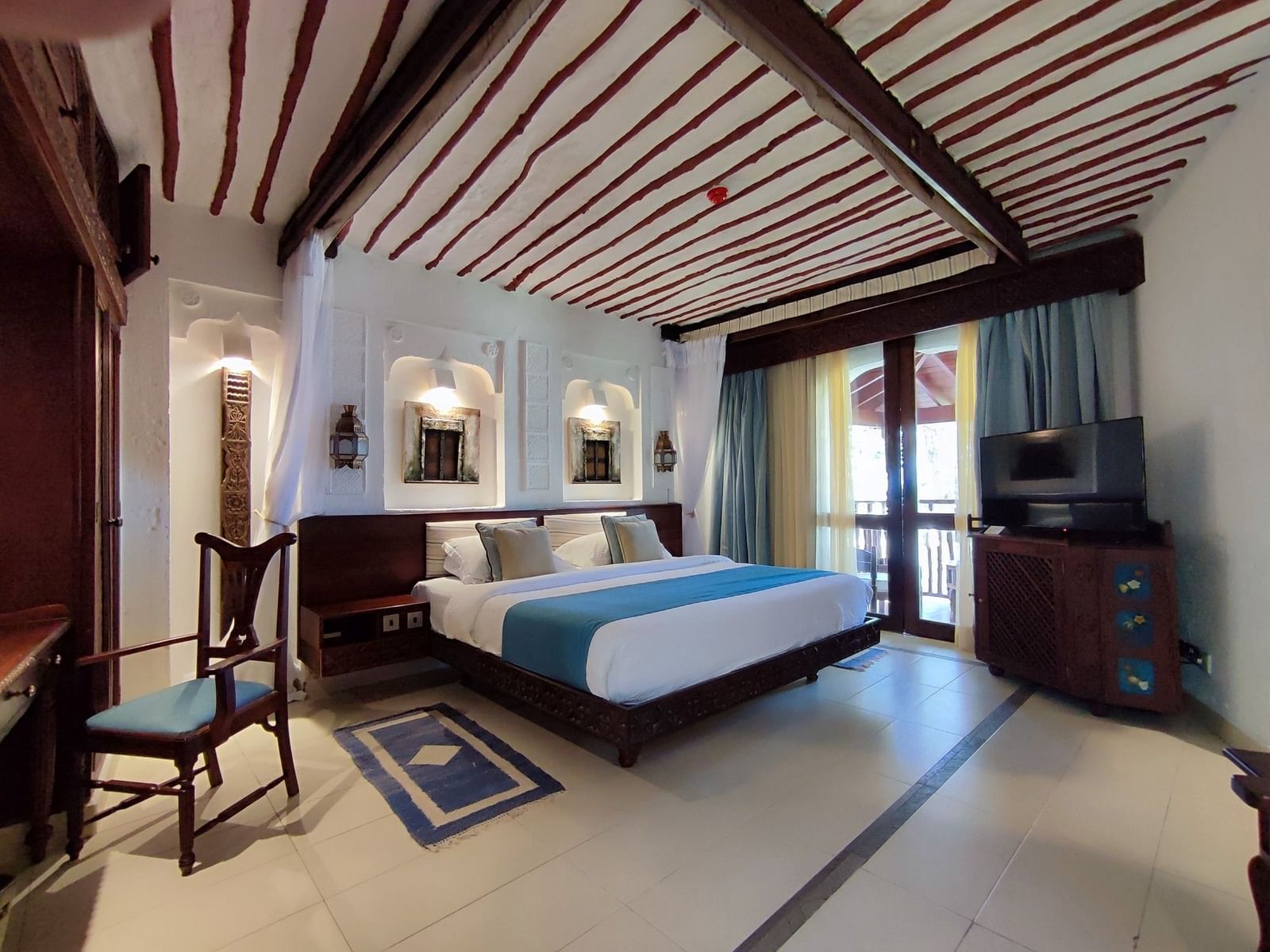 Large bed placed under a wood-slat ceiling decoration at Serena Hotels & Resorts, an apartment resort in Africa