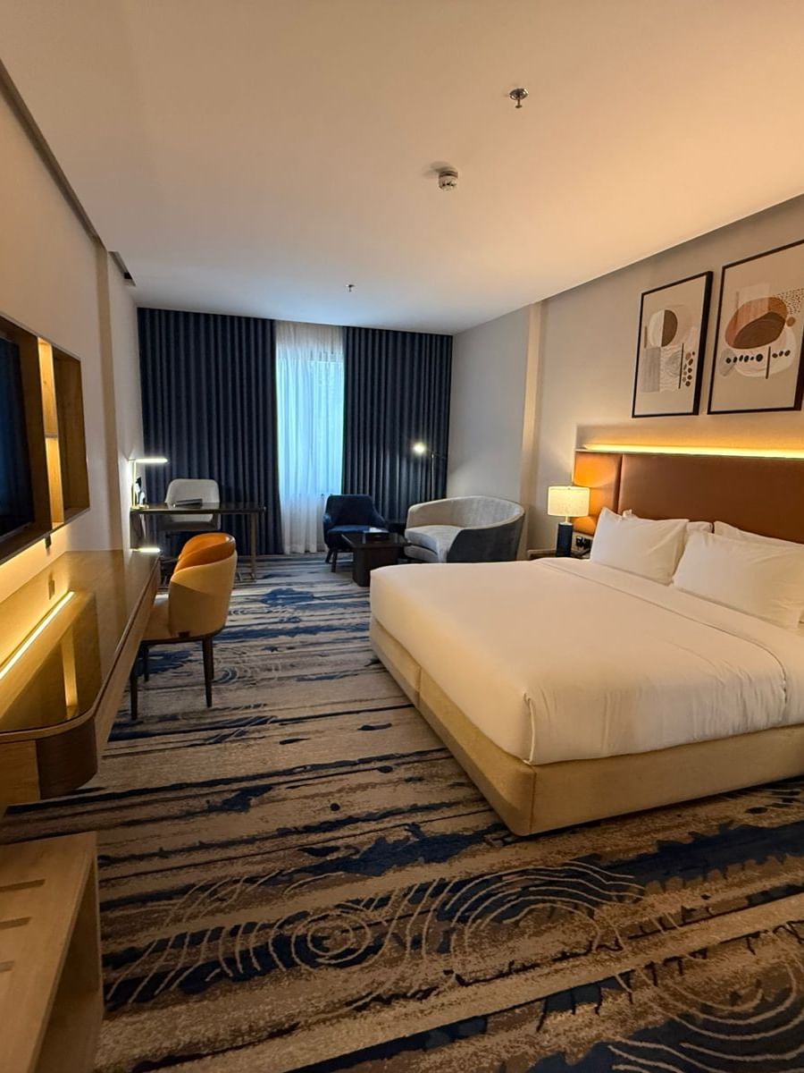 TV and work desk facing the bed beside seating in Premium Club Room at Warwick Jeddah Hotel & Spa