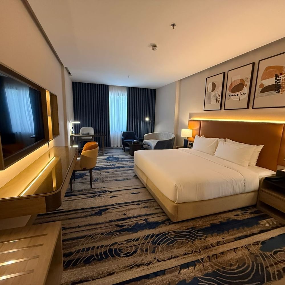 TV and work desk facing the bed beside seating in Premium Club Room at Warwick Jeddah Hotel & Spa