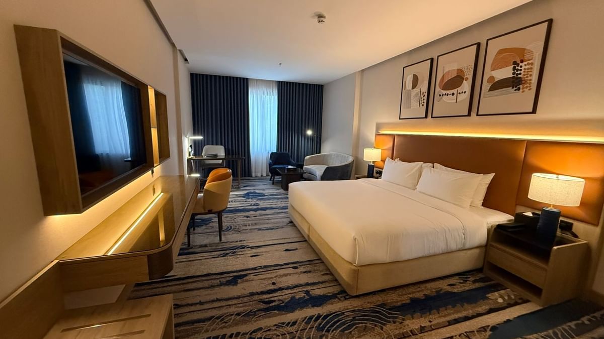 TV and work desk facing the bed beside seating in Premium Club Room at Warwick Jeddah Hotel & Spa