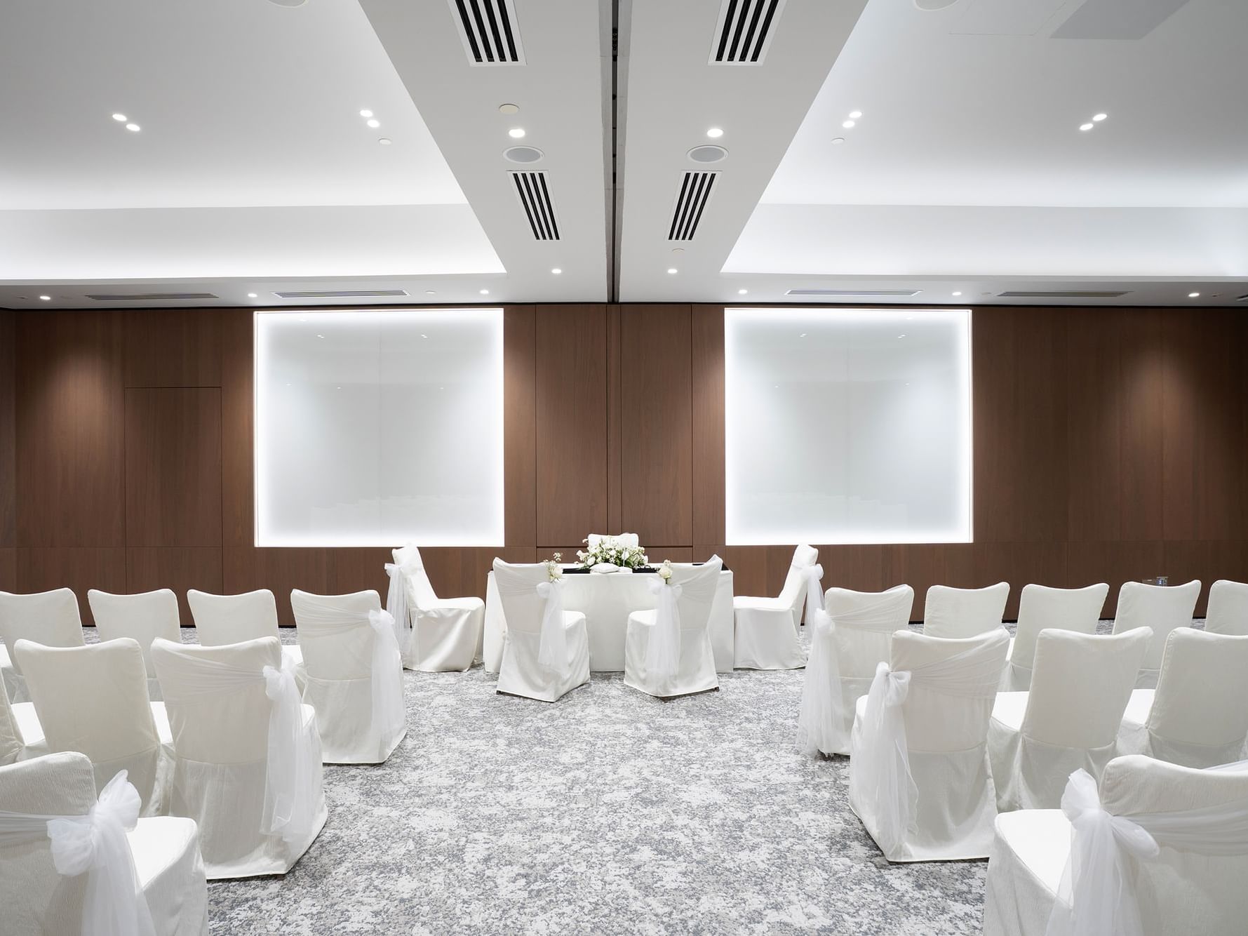 Solemnisation setup in a meeting room at Paradox Singapore, featuring an elegant arrangement with a decorated ceremonial table, chairs for guests, and tasteful floral accents in a bright, intimate setting.