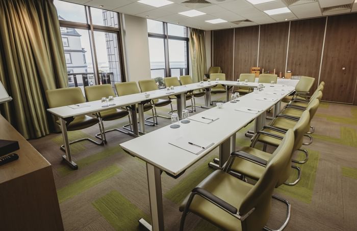 Conference room with U-shaped table arrangement, green chairs and sea views at The View Hotel Eastbourne