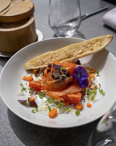 Assiette de saumon fumé garnie de fleurs comestibles et micropousses avec croustillant au Warwick Reine Astrid-Lyon