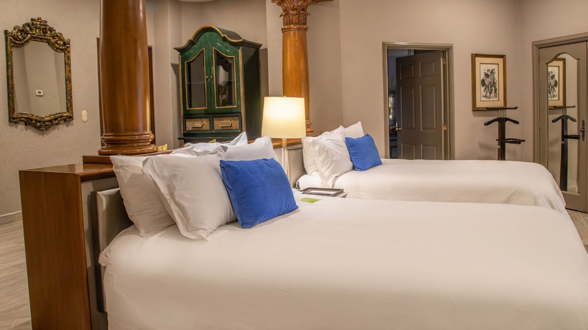 Spacious room with two double beds, white linens, blue accent pillows, and colonial-style furnishings at Quinta Real Guadalajara