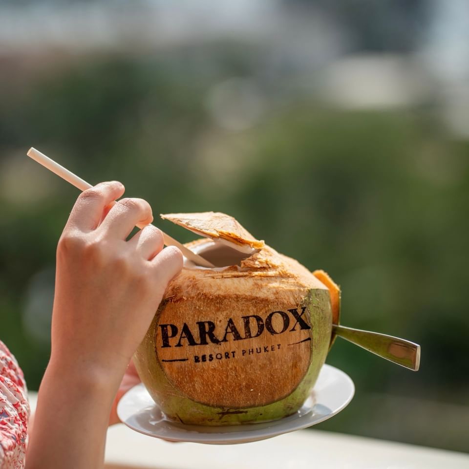 A person about to enjoy a fresh coconut that is branded 