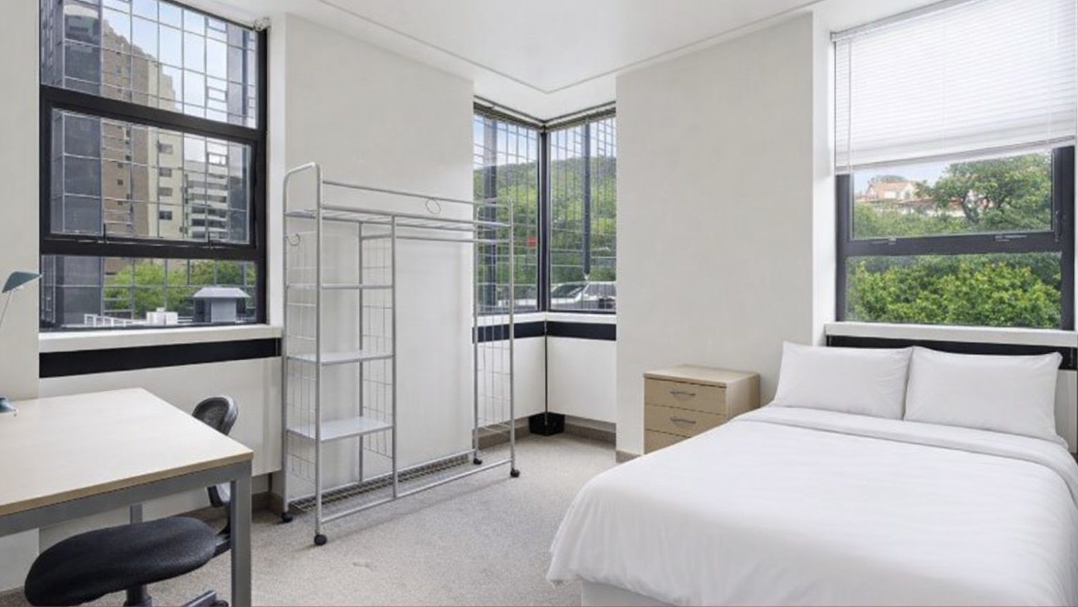 White room with desk, metal shelf, and bed at UniLodge Stafford House.