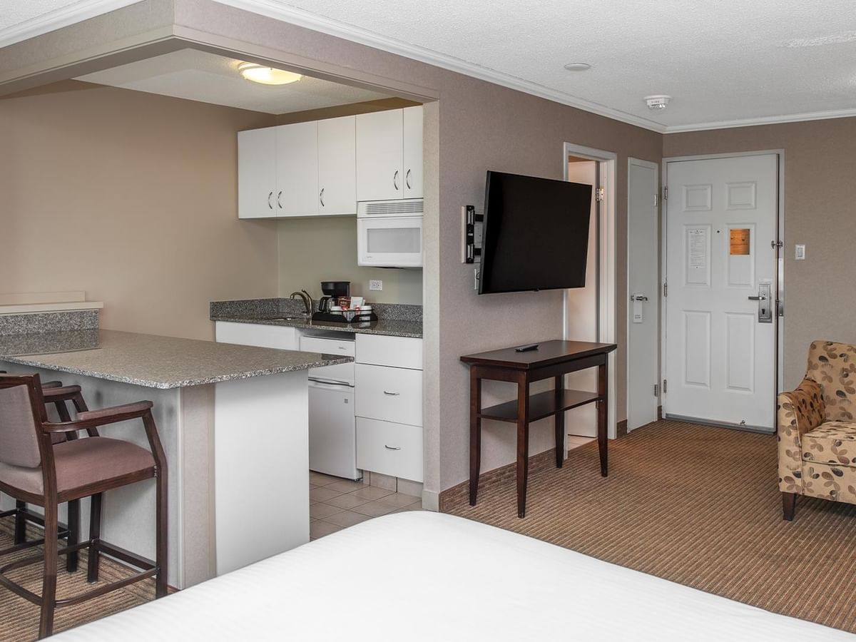 Hotel suite kitchen and dining area with a TV and small table.