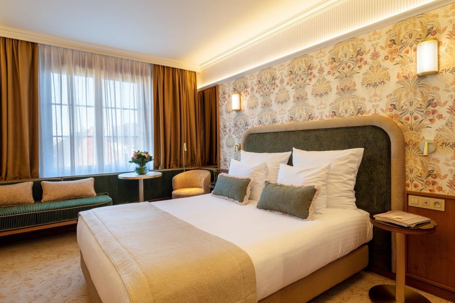 Elegant hotel room with floral wallpaper, plush bedding, and warm lighting at Warwick Brussels Grand-Place