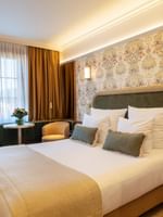 Superior Room with floral wallpaper, king bed, seating area, and large windows at Warwick Brussels Grand-Place