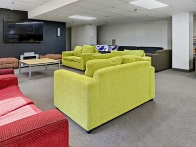 Modern lounge area with colorful couches, a TV, and a bookshelf at UniLodge Stafford House.