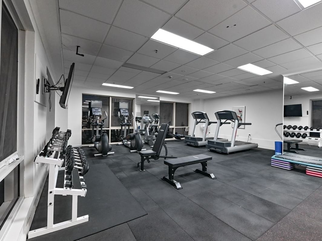 A fitness center with workout machines and mirrors at Nesuto Canberra Apartment Hotel