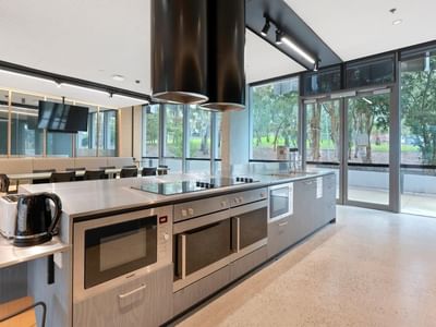 Modern kitchen area with stainless steel appliances and glass doors at La Trobe University.