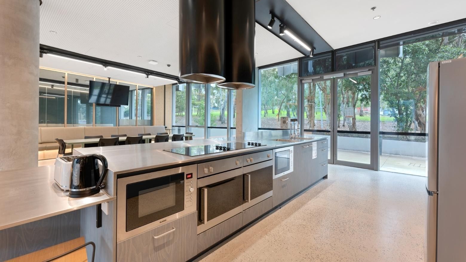 Modern kitchen area with stainless steel appliances and glass doors at La Trobe University.
