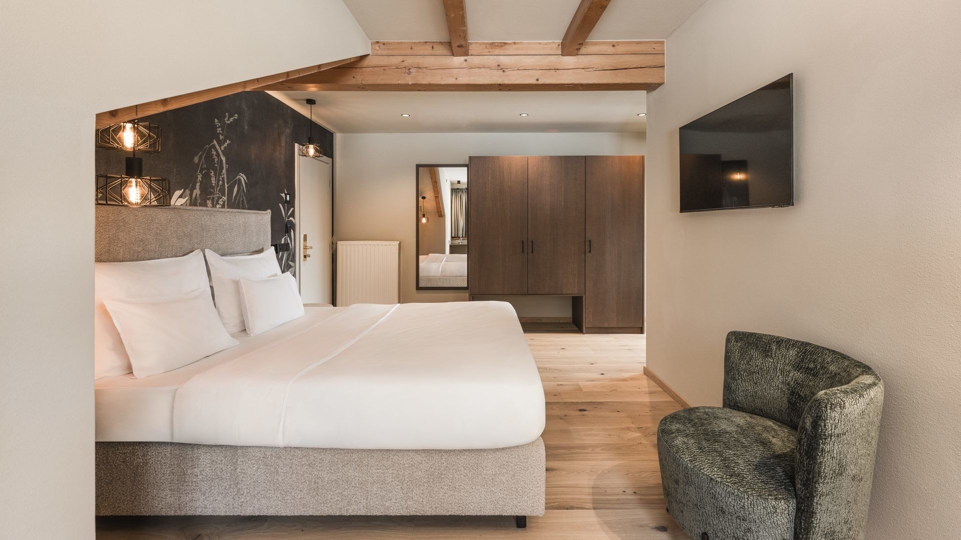 Gemütliche Junior Suite Talblick mit Kingsize-Bett und Sessel am Falkensteiner Hotel Antholz.