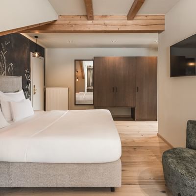 Gemütliche Junior Suite Talblick mit Kingsize-Bett und Sessel am Falkensteiner Hotel Antholz.