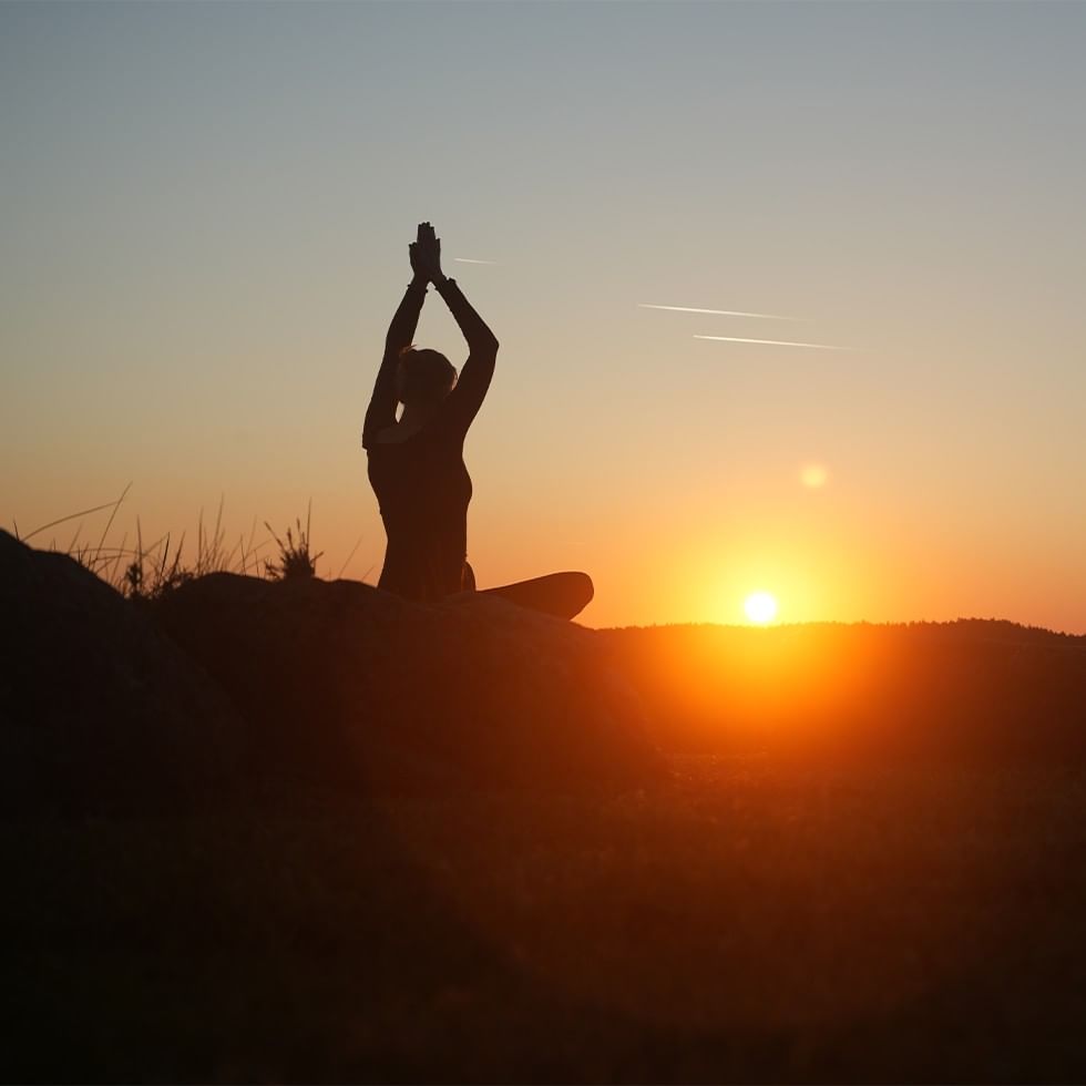 A person practicing yoga at sunset for summer solstice celebration.