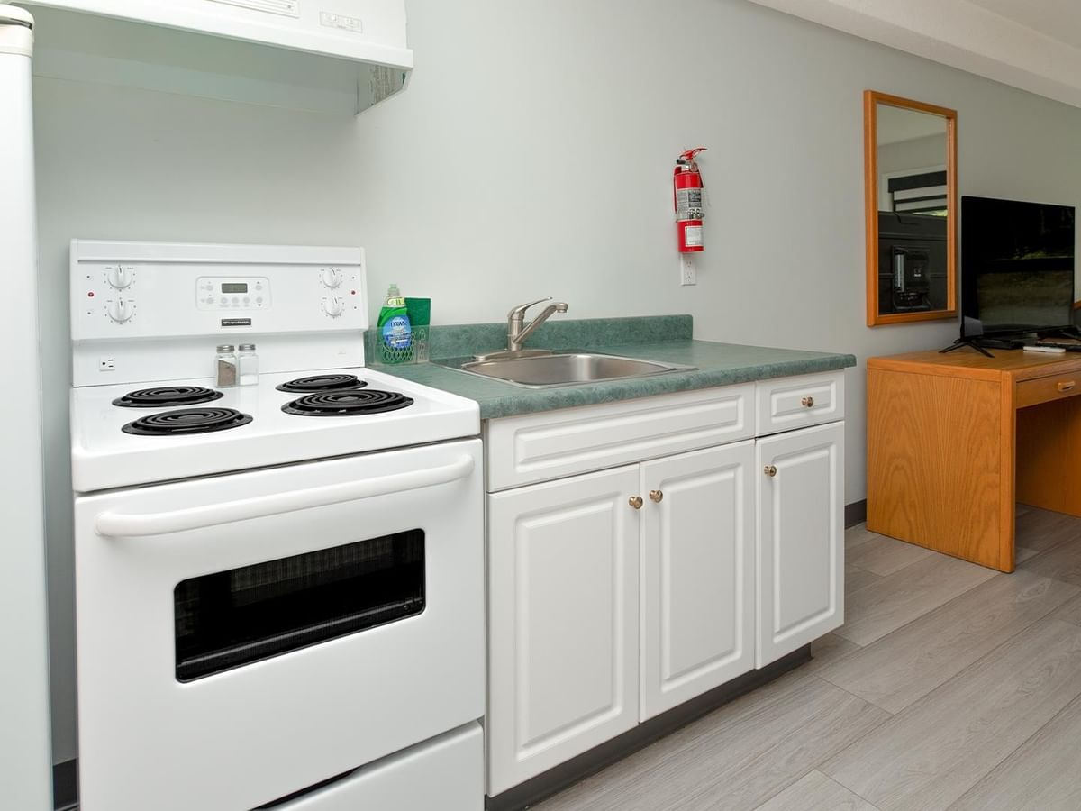 Coast Two Queens with Kitchenette featuring white stove, sink and wood furnishings.