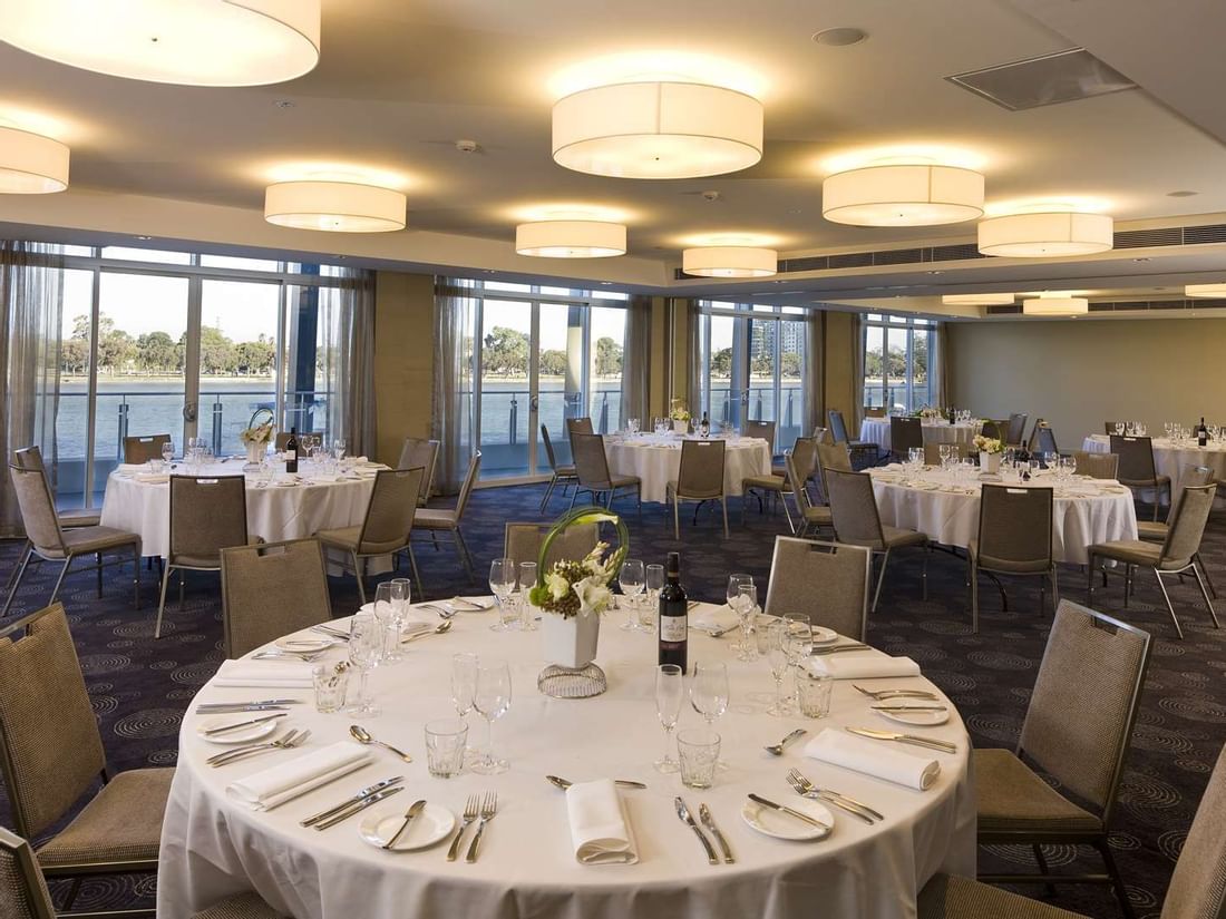 Spacious, elegant ballroom at The Sebel Mandurah set for a wedding reception with round tables and large windows