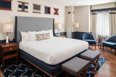 Two ottomans & lounge chairs by the bed in Deluxe Rooms at Portland Harbor Hotel