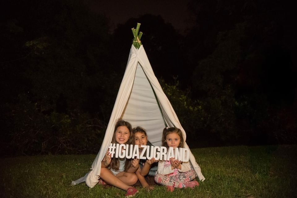 3 niños en una carpa en un jardín en Iguazu Grand Resort por la noche