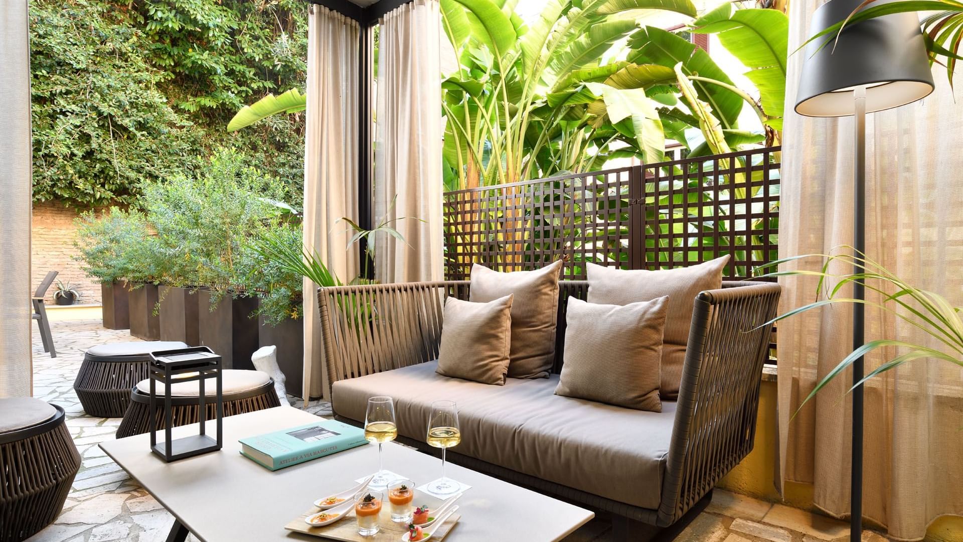 Lounge area with comfy seating and a coffee table with a greenery backdrop in Garden Suite at Margutta 19