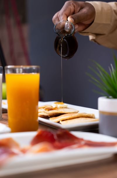 Hand pouring syrup on pancakes in restaurant at Panama Hotel