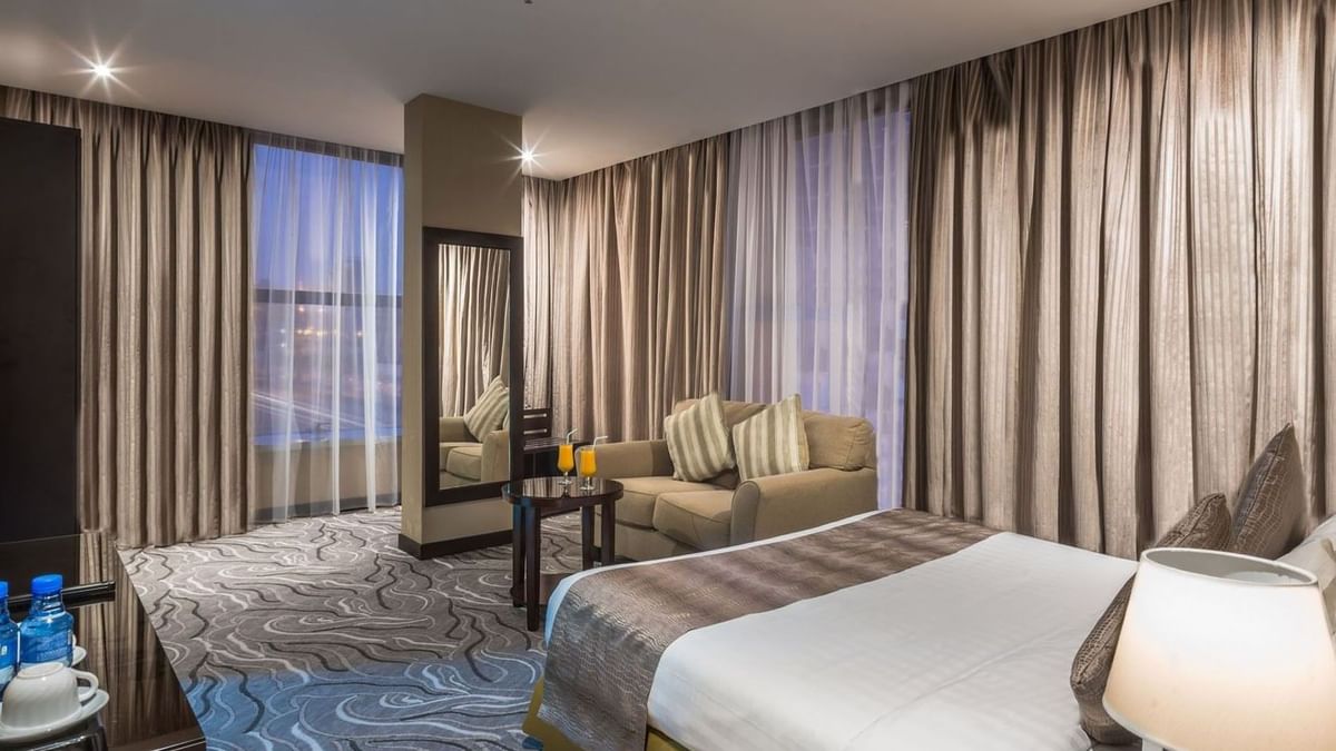 Modern lounge chair by a tall mirror under soft ceiling lights in Executive Suite Sea View at Naviti by Warwick Al Khobar