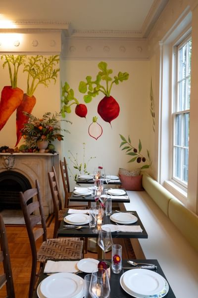Dining room with vegetable mural on walls and set tables beside a window at The Ashbrook Hotel