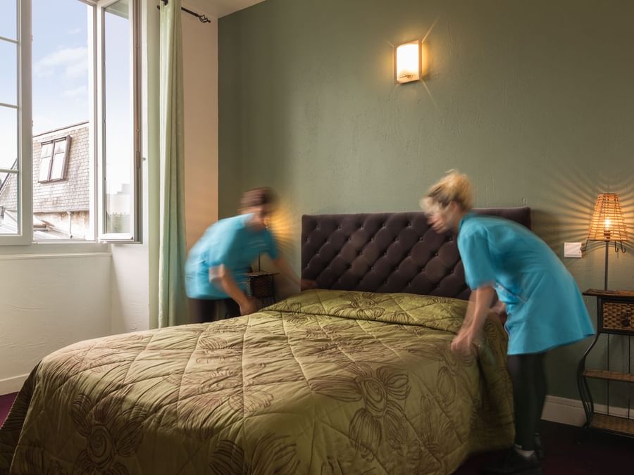 Two ladies arranging a bed in a room at Villa Montpensier
