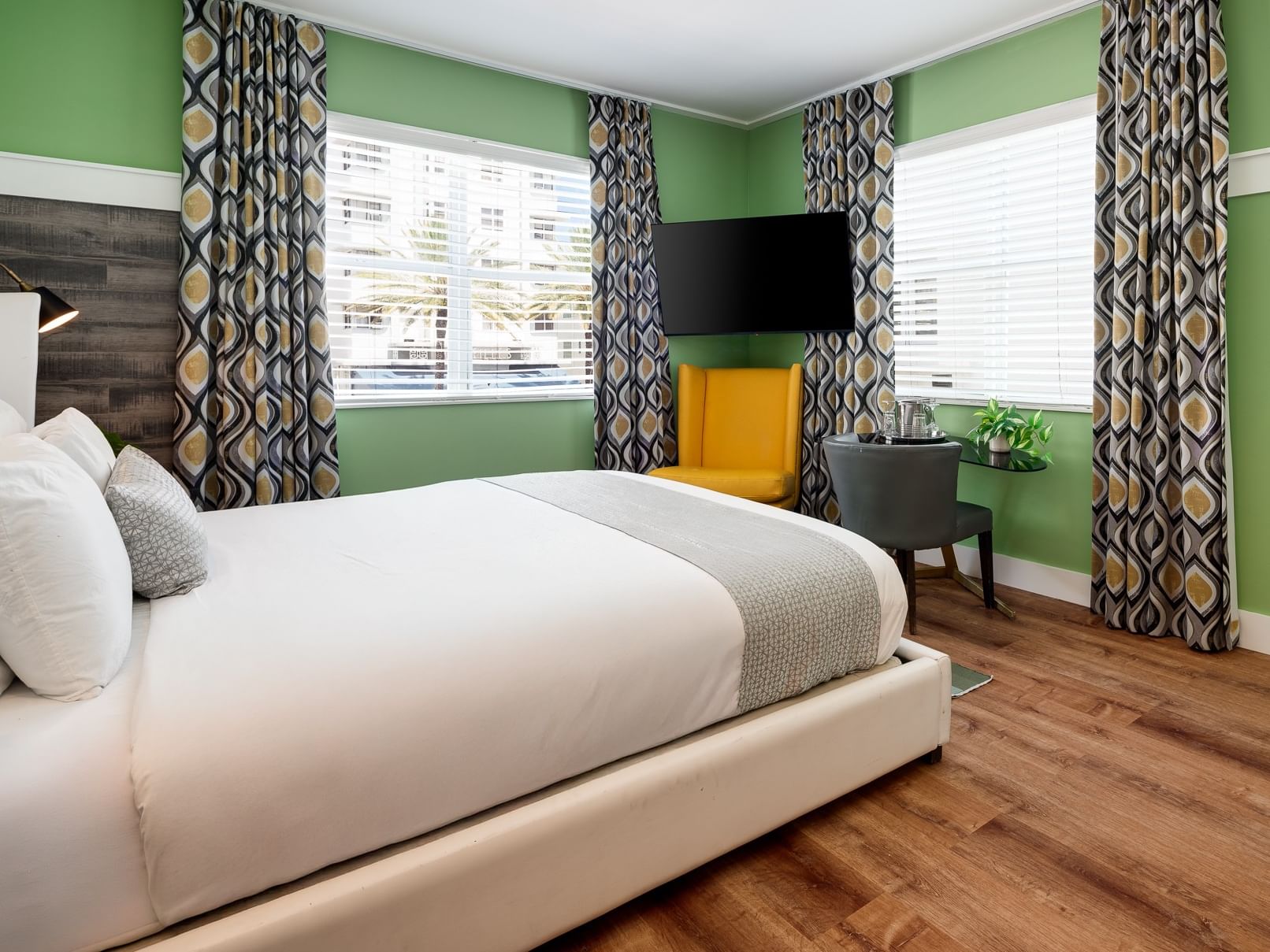 A hotel room with a large bed, TV, and window