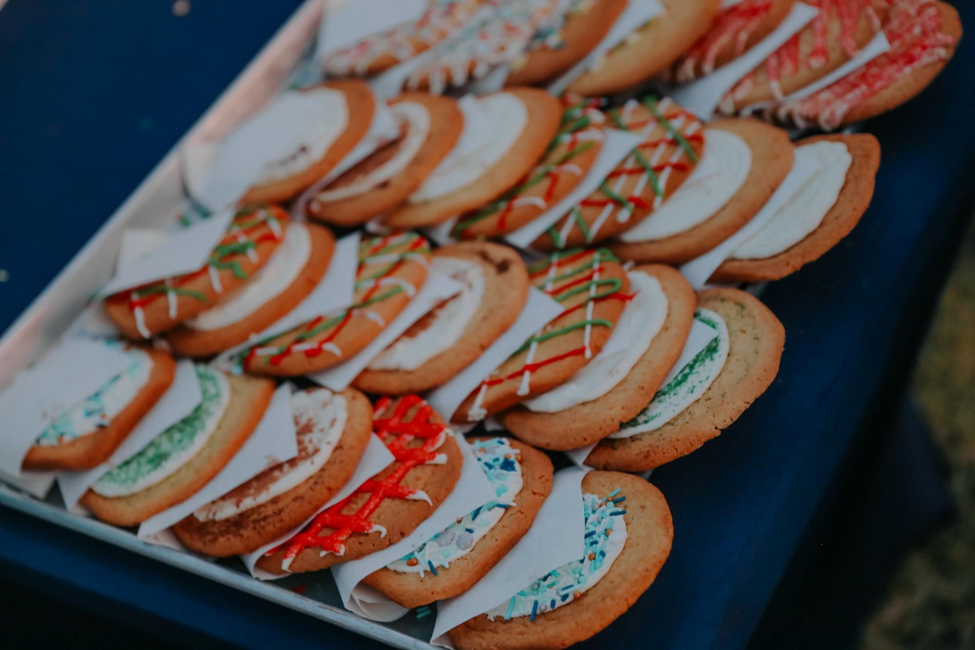 A tray filled with iced cookies with colorful sprinkles on top of a blue table.