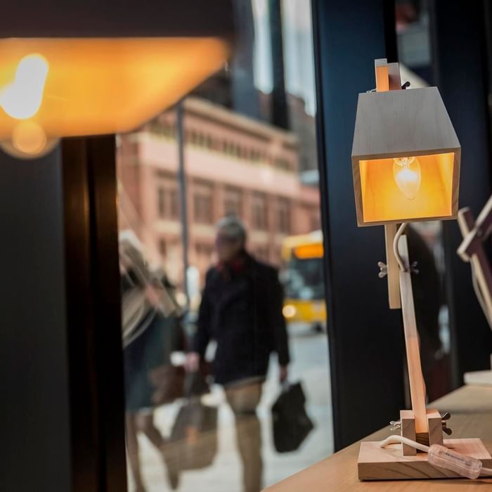 Stylish wooden desk lamps displayed by the window with a blurred street scene beyond at Ibis Adelaide