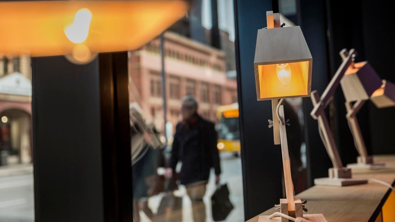Stylish wooden desk lamps displayed by the window with a blurred street scene beyond at Ibis Adelaide