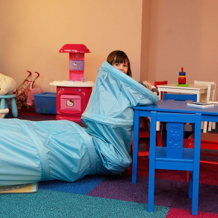 Colorful playroom with a small blue table, chairs, and assorted toys at Falkensteiner Family Resort Lido