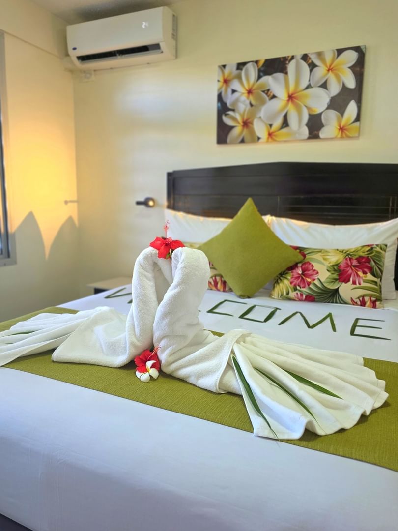 Suite featuring leaf arrangement and heart-shaped towel swans with red hibiscus flowers at TokaToka Resort Nadi Fiji